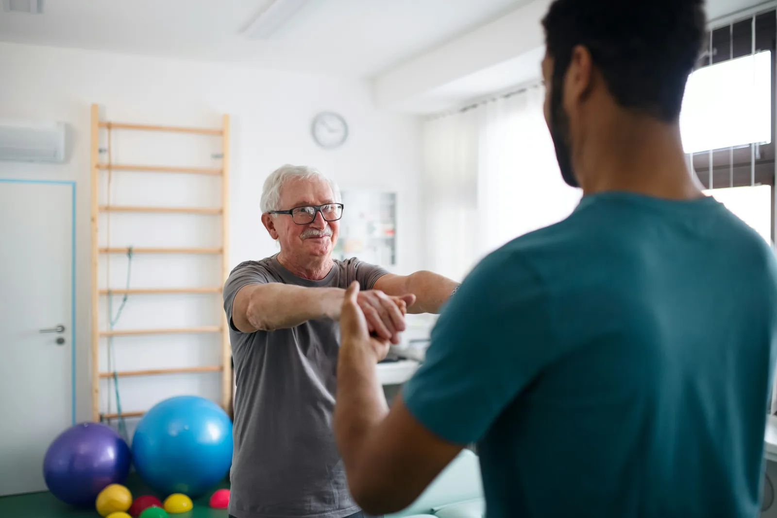 Physiotherapeut arbeitet mit einem älteren Patienten an einer Übung