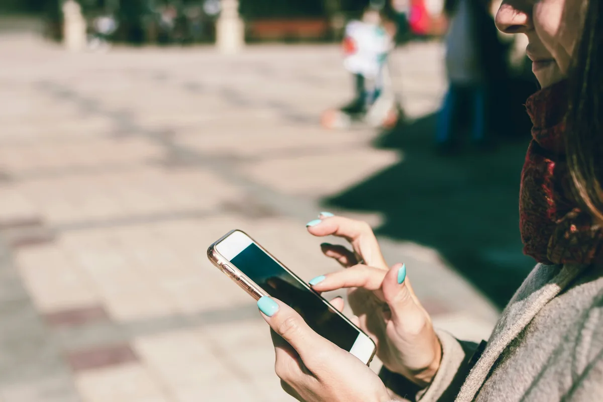 Junge Person schaut auf dem Smartphone nach einem Arbeitgeber